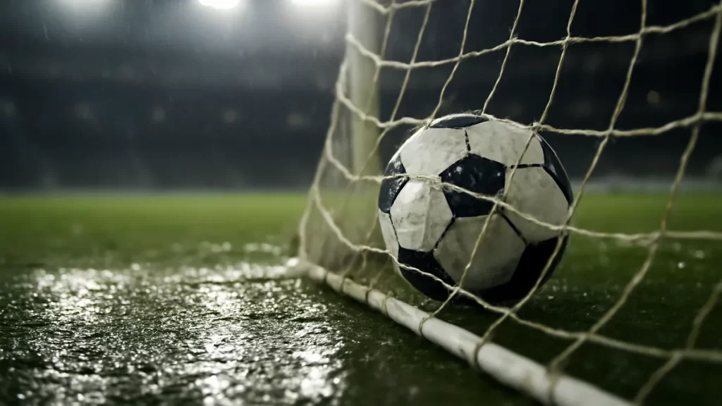 South Africa end Nigeria’s Women’s World Cup streak as Ghana advance Wet football caught in goal net beneath floodlights, empty blurred stands.