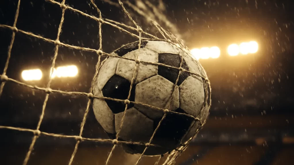 Fishlock brace breaks Reign scoring record in 2-0 win Wet football resting in goal net beneath glowing floodlights and blurred stands